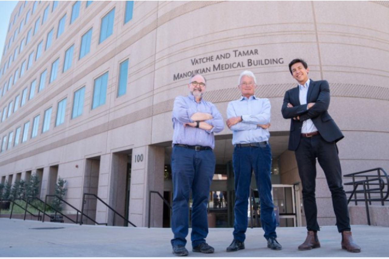 Three men stand confidently outside a medical building, arms crossed, smiling.