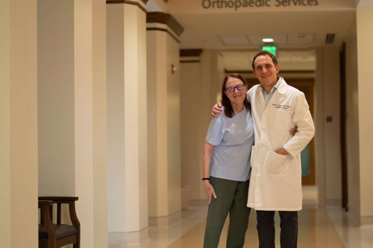 Jaqueline Hansen and Dr. Andy Jensen stand in front of an Orthopaedic Services sign.