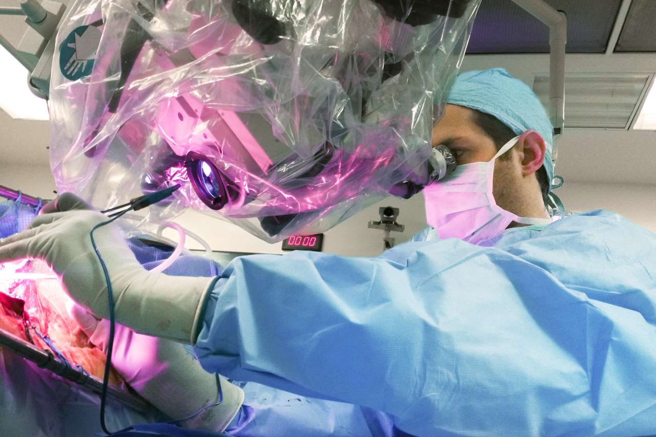 Richard Everson performing brain surgery, looking through a device inside of an operating room
