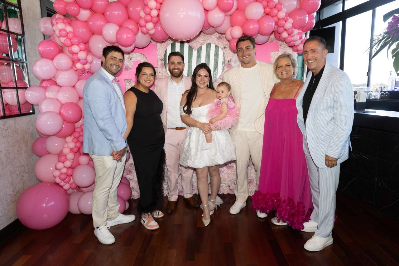 Joanne Slobodien with her family posing in front of a wall decorated with pink balloons of different sizes.