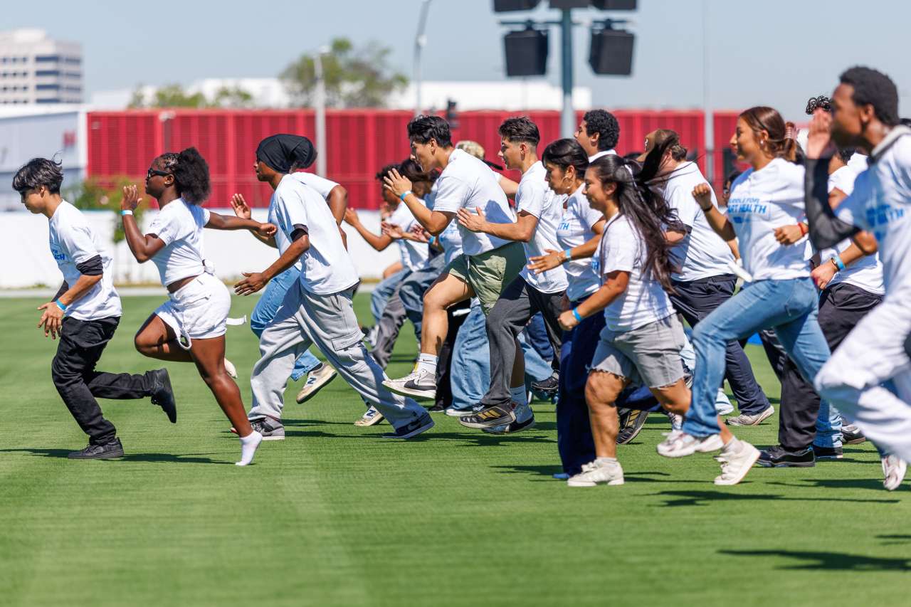High school students run on the Chargers practice field.