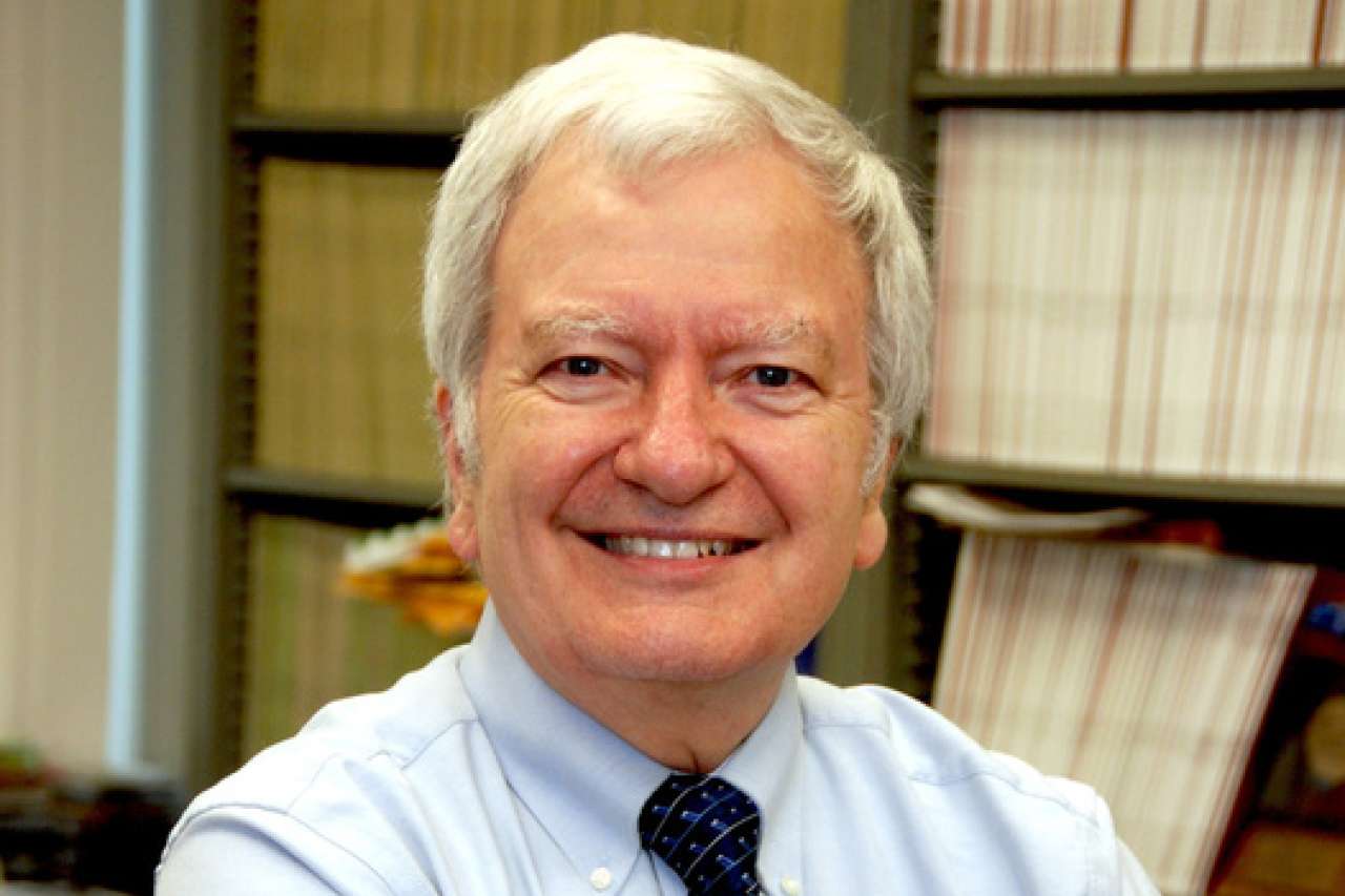 Business professional with arms crossed, wearing a light blue shirt and patterned tie.