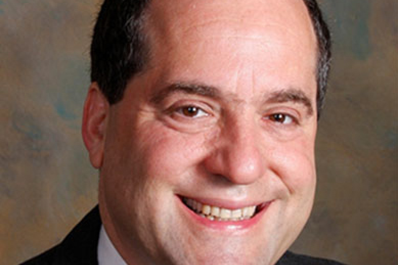 Professional headshot of a smiling man in a suit and tie