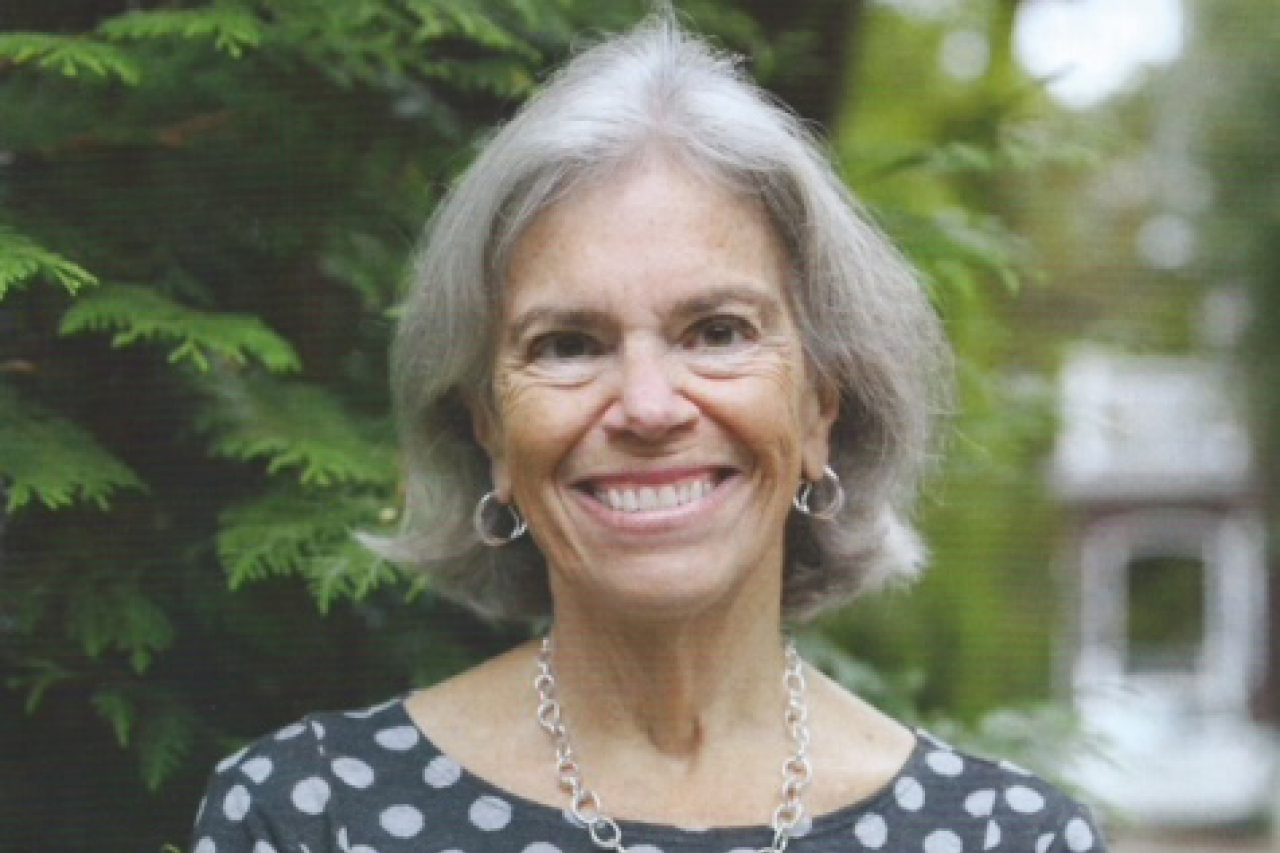 Smiling older woman with gray hair in polka-dot blouse outdoors