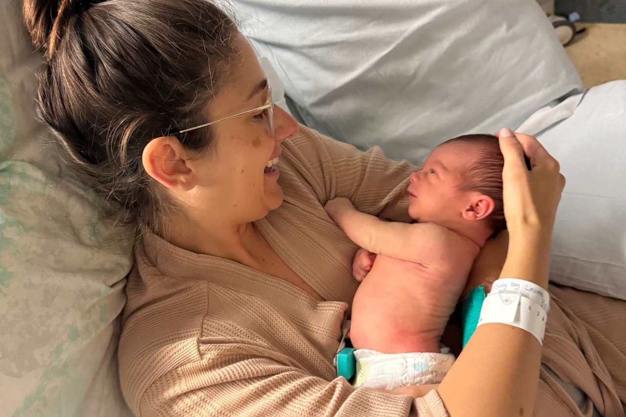 A mom holds her newborn in a hospital bed.