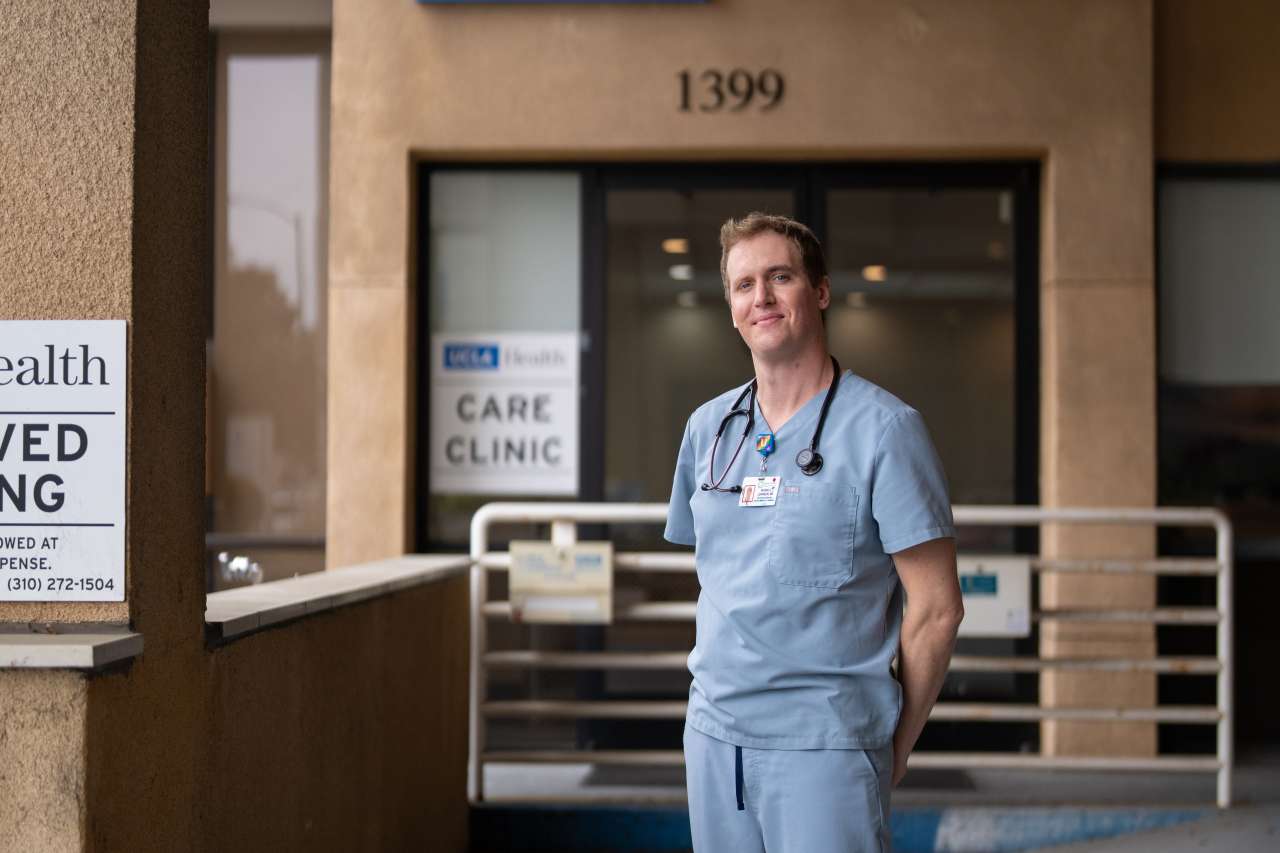 Man with scrubs in front of hospital entrance