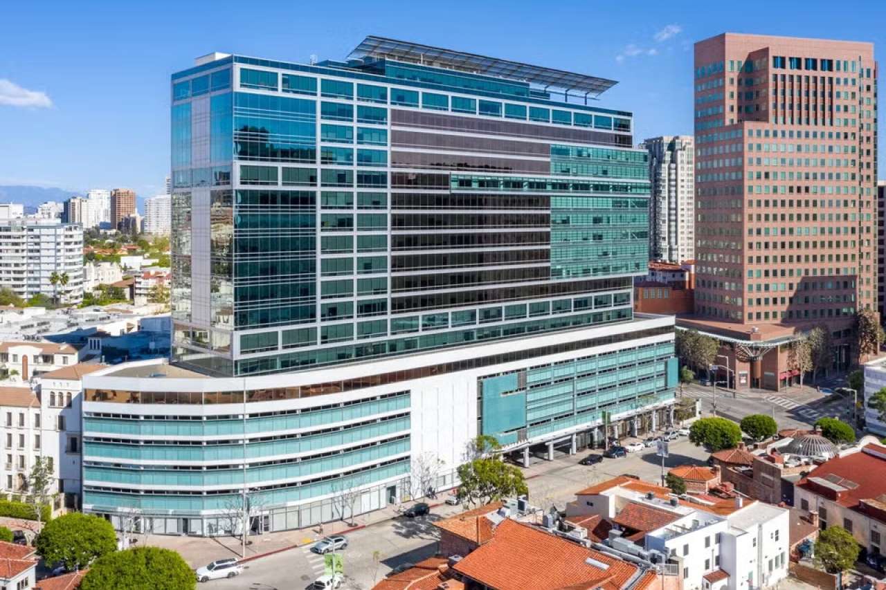 Large modern glass office complex with adjacent high-rise buildings in city.