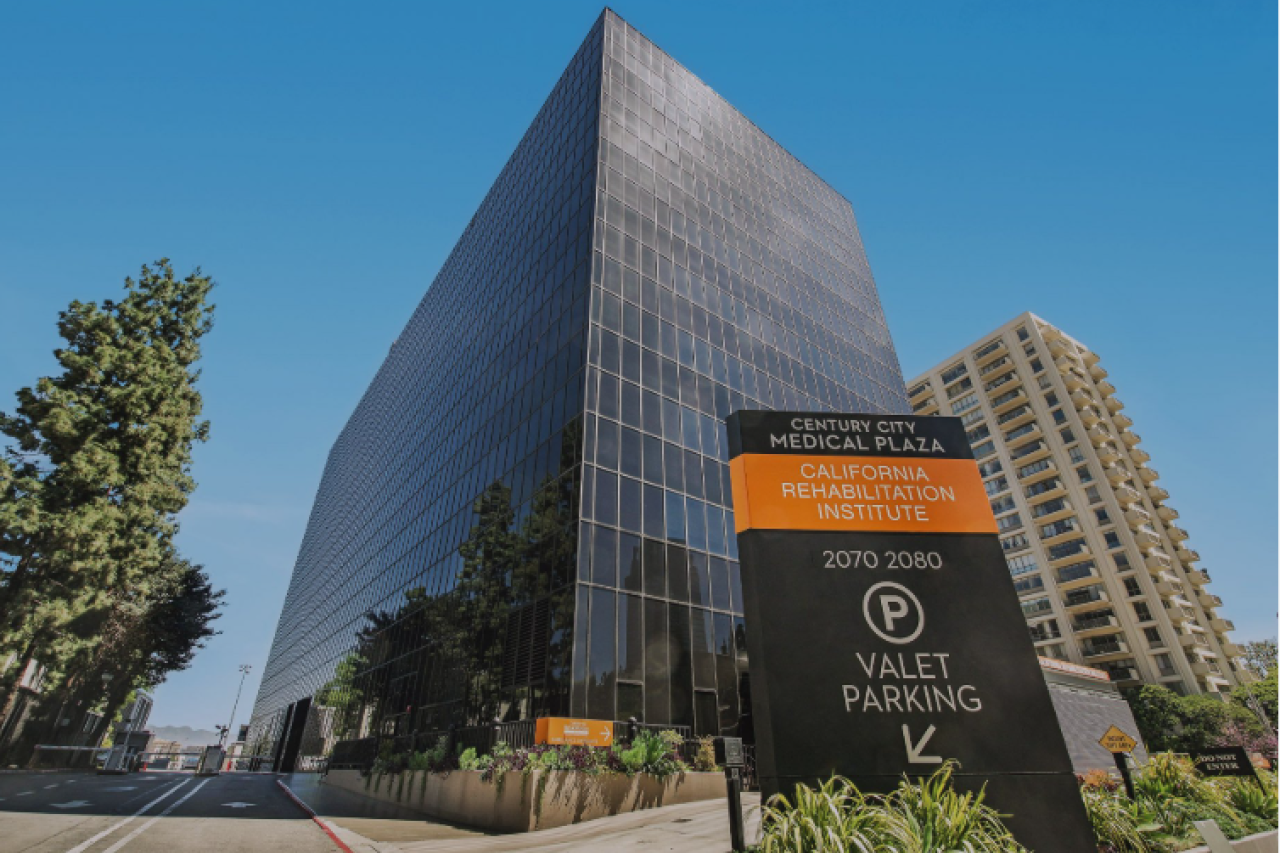 Modern glass office tower with valet parking sign.