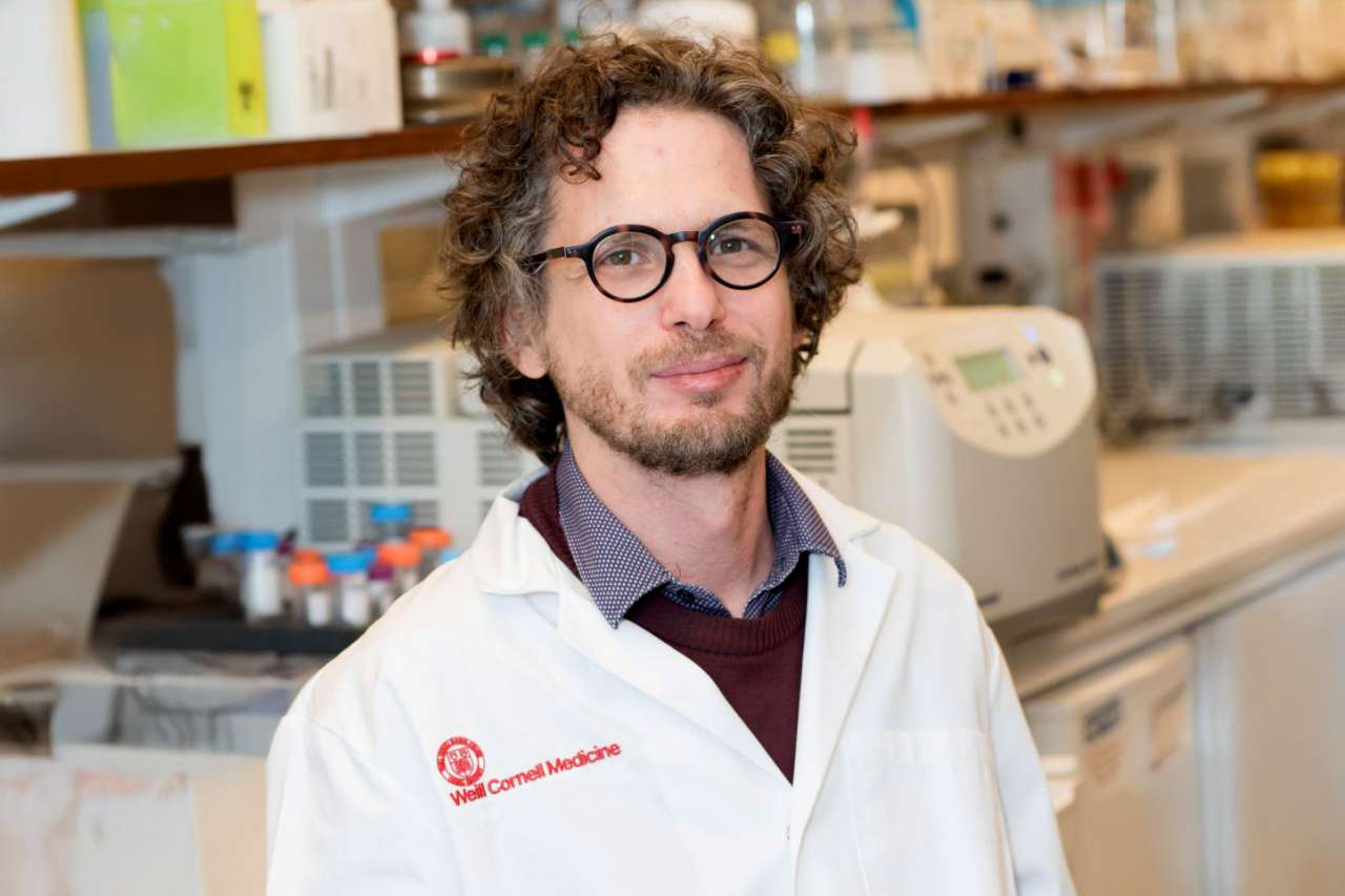 Dr. Dan Landau wearing a lab coat and glasses in a laboratory