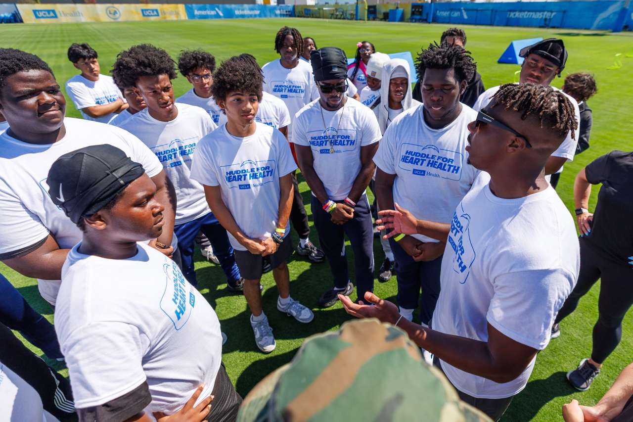 A football player talks to students on the practice field.