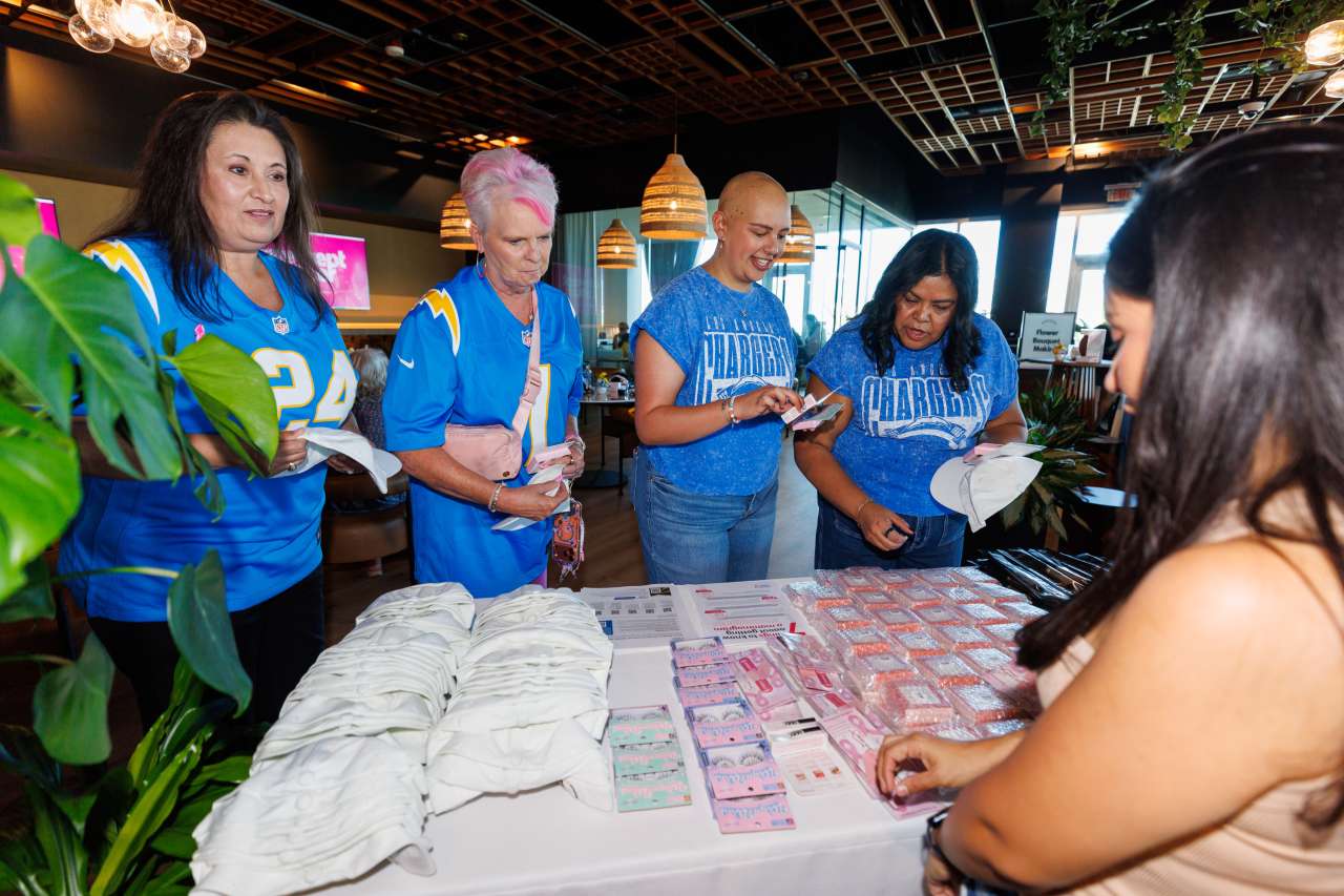 A group of women look at cosmetics displayed on a table.