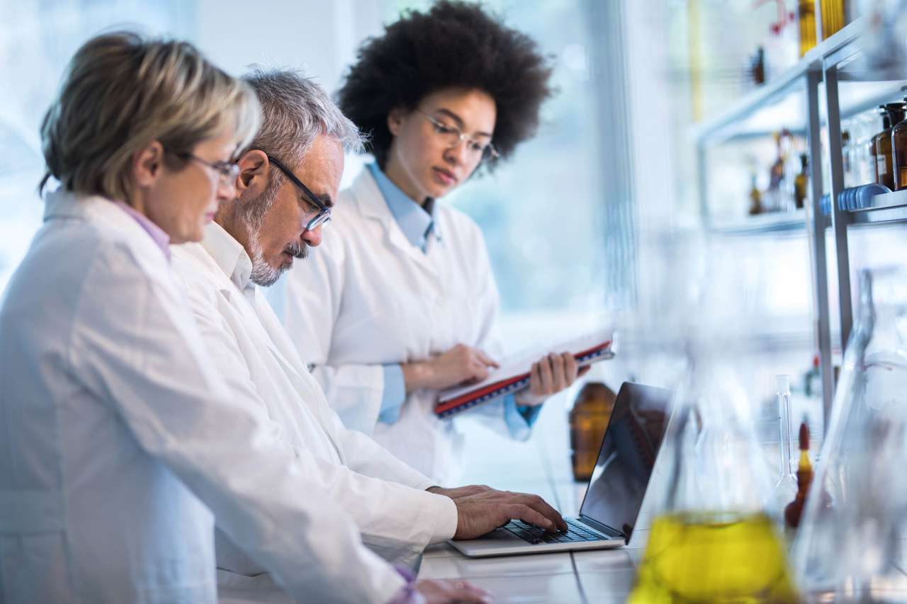Researchers standing and discussing a presentation in a lab