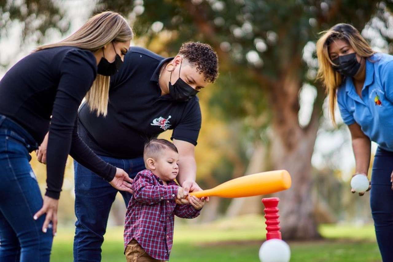 Volunteer assisting child with t-ball