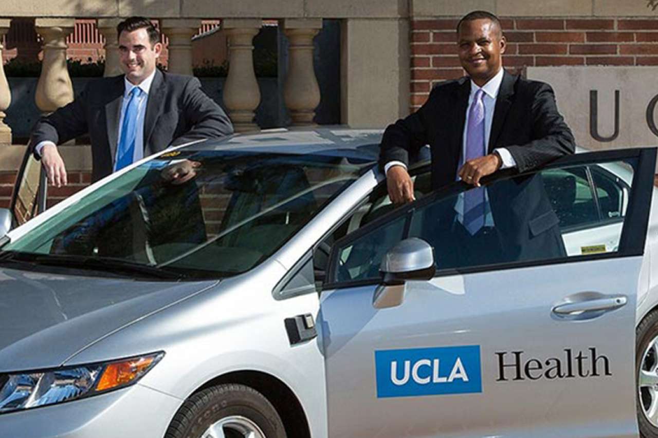 A couple of professionally dressed men standing by a UCLA Health vehicle