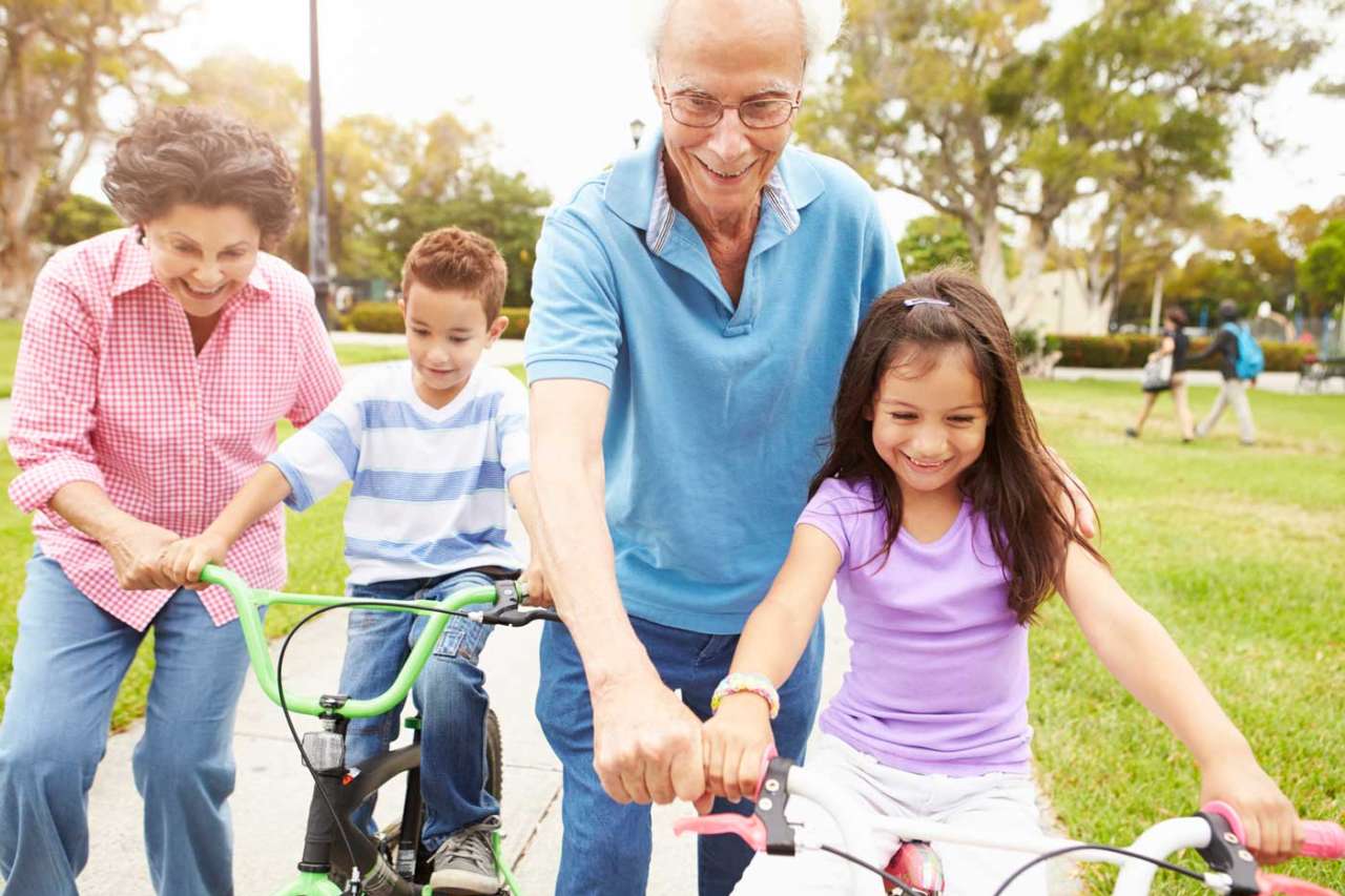 Grandparents guiding their grandchildren on bicycles at a park