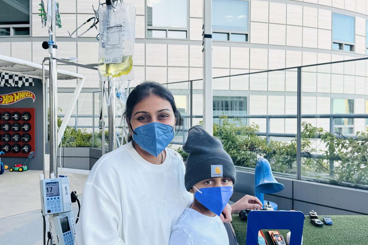A mom and son stand outside a hospital.