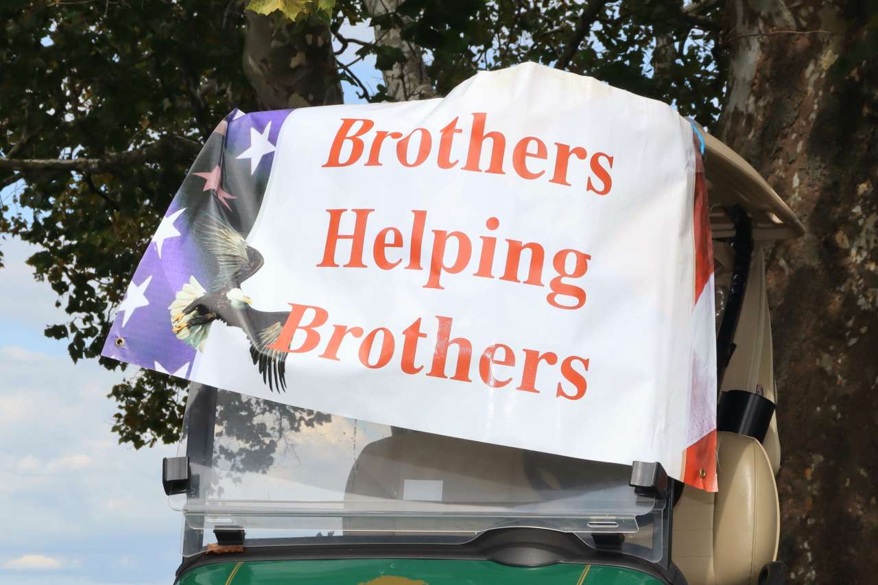 Sign reading "Brothers Helping Brothers" attached to a golf cart