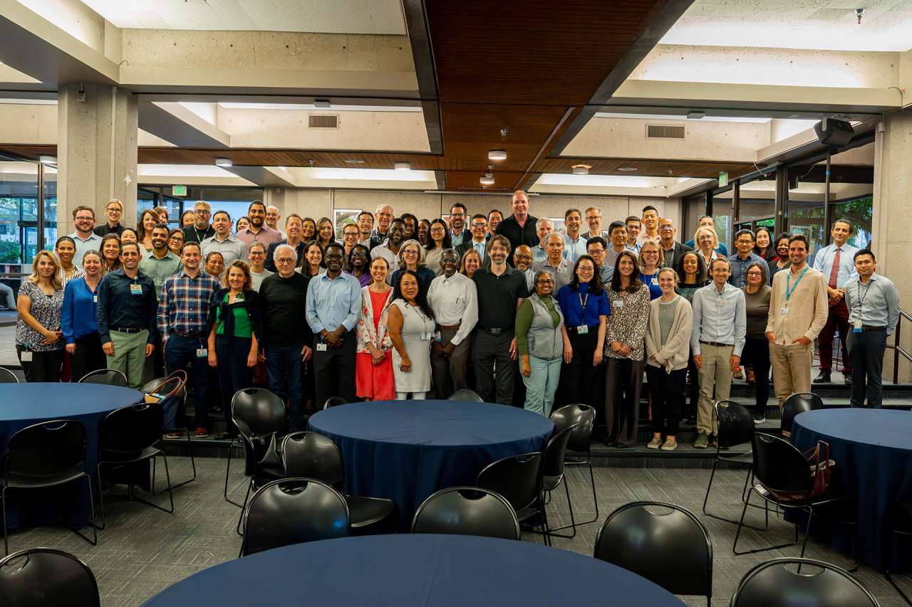 Large group of people posed in a conference room with round tables