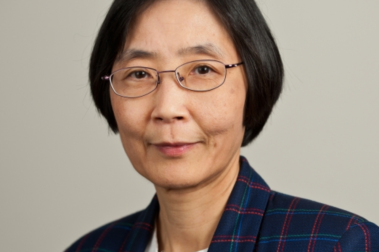 A person wearing a plaid blazer, facing forward against a neutral background.