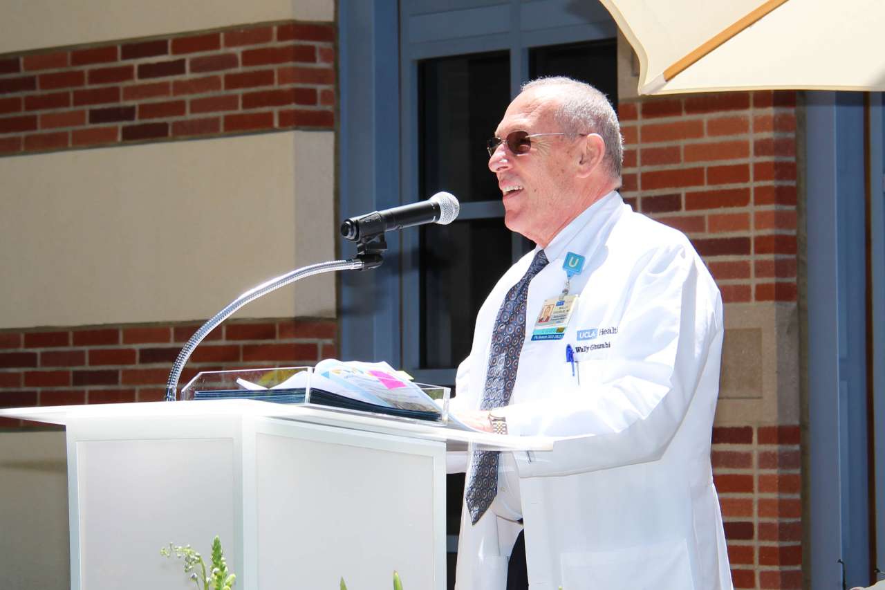 UCLA Health doctor in white lab coat speaking at a podium.