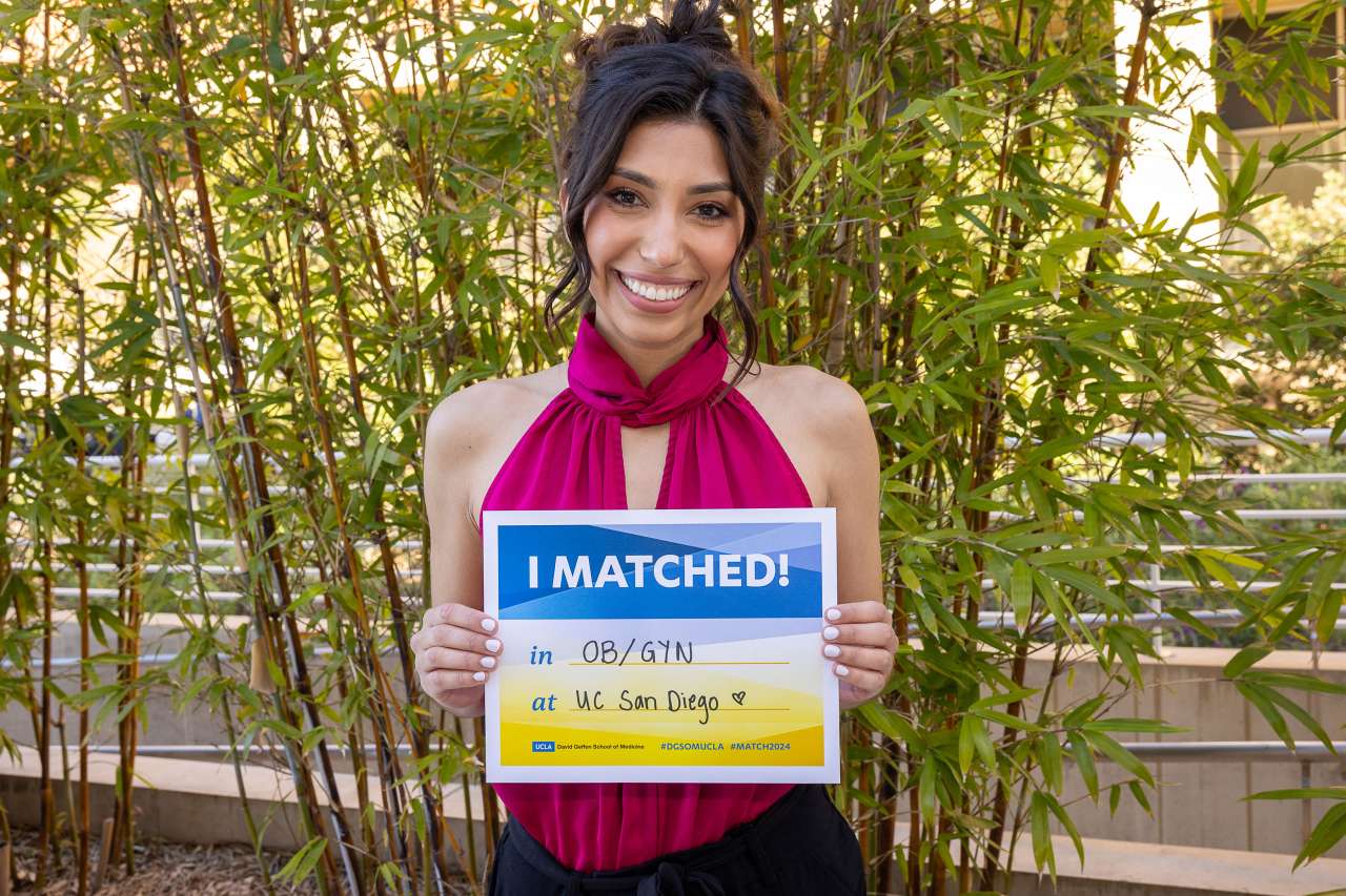 Leilani Gutierrrez-Palominos standing with a sign that states I matched at UCSD for OB-GYN.