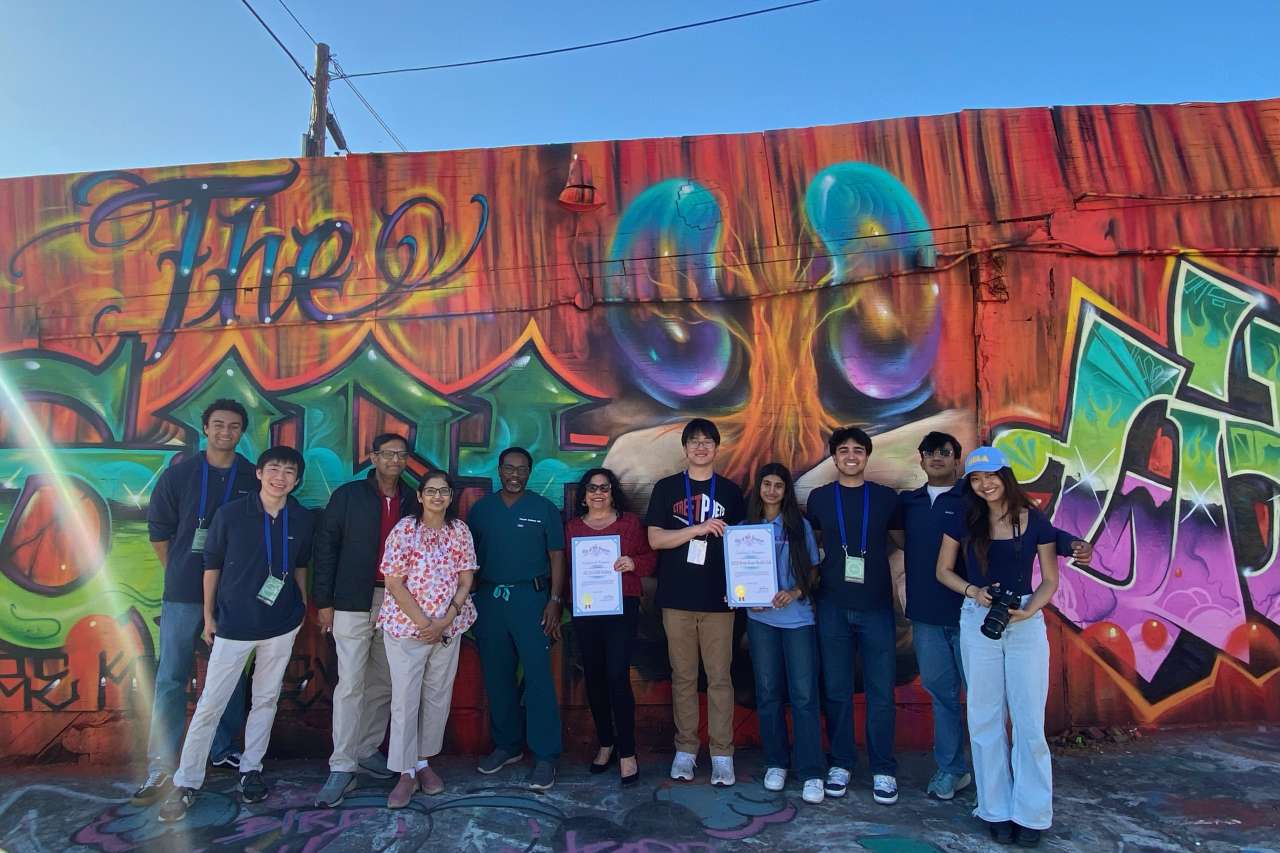 Group photo in front of a colorful graffiti wall, holding certificates.