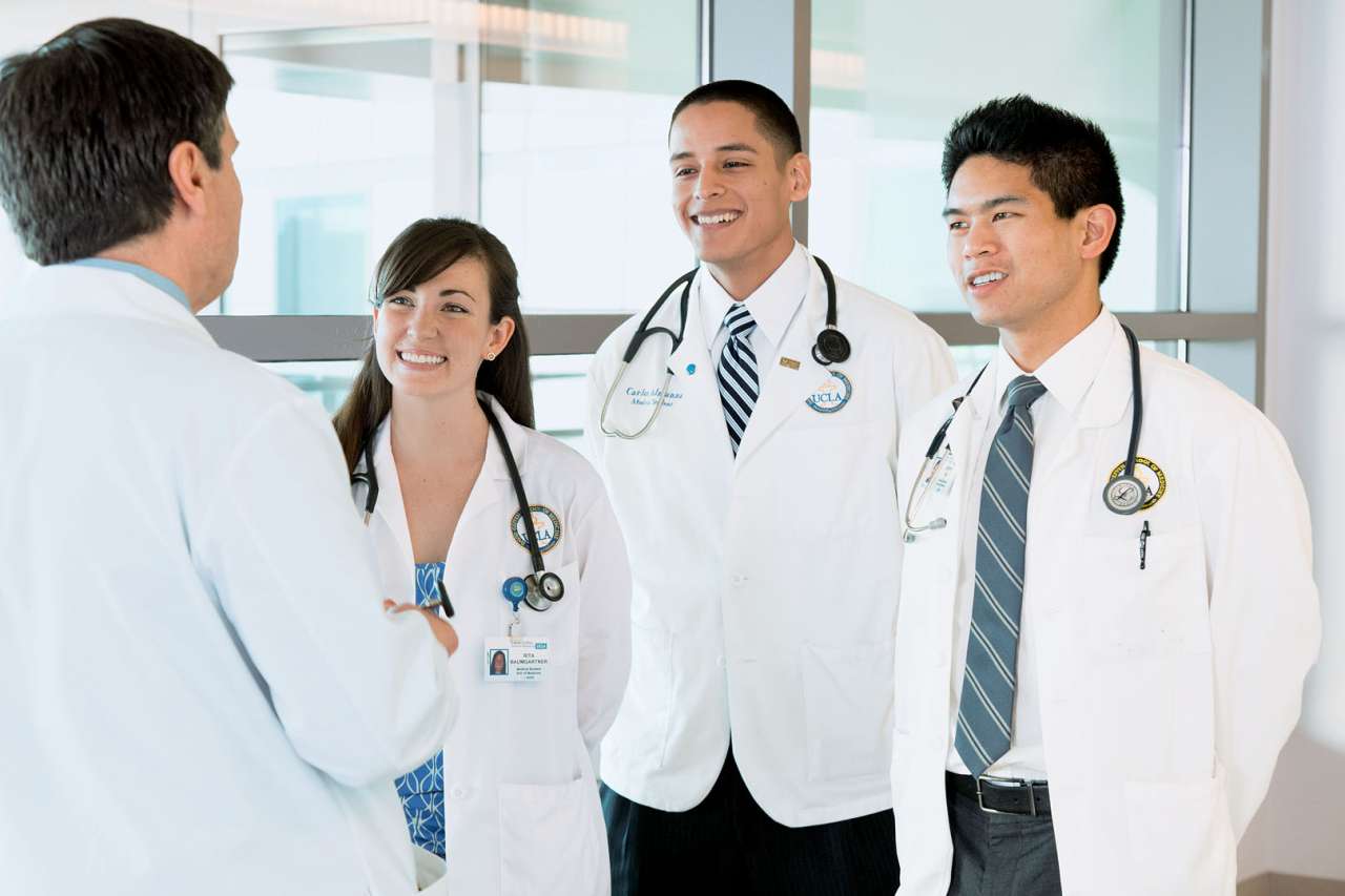 Medical students smiling and looking at a teacher.