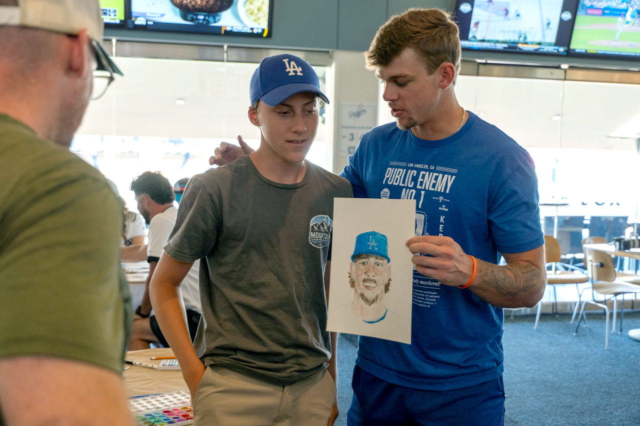UCLA Health patient Keaton and his father meet Dodgers pitcher Gavin Stone an art workshop, with Gavin holding the portrait Keaton drew of him
