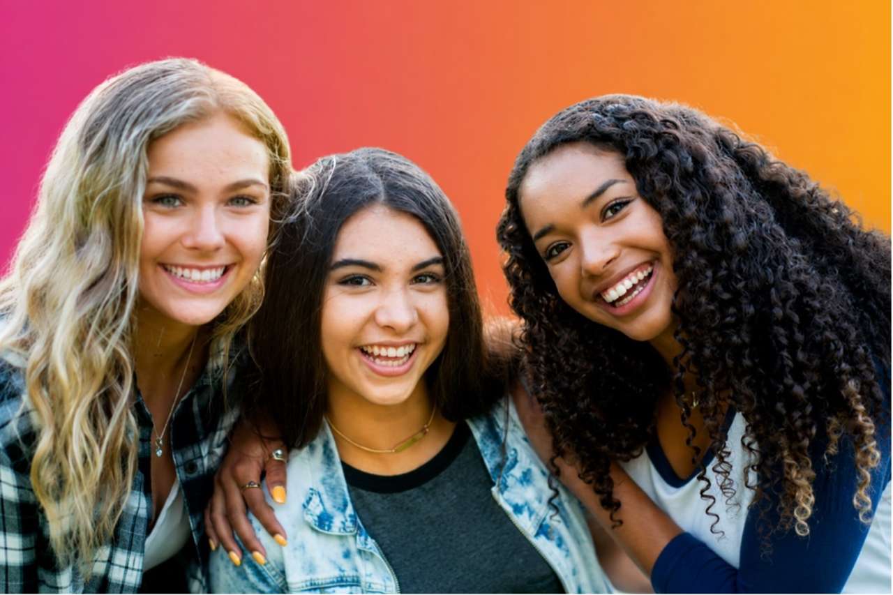 Three young adults from a range of backgrounds smile and pose together against a colorful pink-to-orange gradient background. The image represents connection, community, and participation in health research among young people.