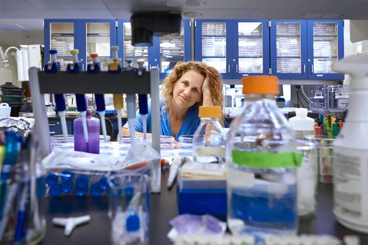 Laboratory scene with glassware and Dr. Joanne B. Weidhaas in the background.