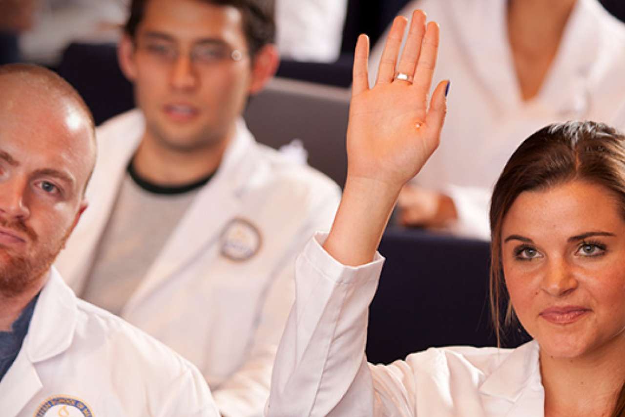doctor raising her hand in a lecture hall