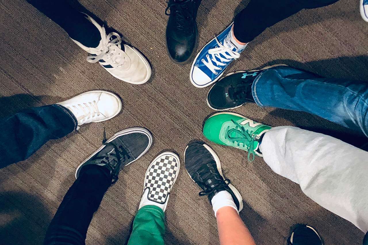 several teens putting their leg out forming a circle with their shoes