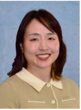 Woman with shoulder-length dark hair in beige collared sweater, face blurred on blue backdrop