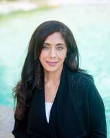 A woman with long black hair wearing a black cardigan.