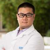 Huiming Dong, PhD in a white coat.