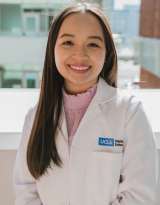 Serinee Tran, who has brown hair, wearing a whitelab coat and pink blouse