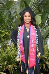 graduation photo of Reeanna, who is wearing a graduation cap and a red stole