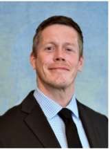 Person wearing suit and tie against blue background.