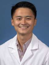 Dr. Matthew Du smiling at camera in a white coat