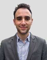 A person in gray suit and blue shirt on gray background