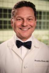 Dr. Brandon Koretz in a white lab coat and bow tie, smiling and exuding professionalism and confidence.