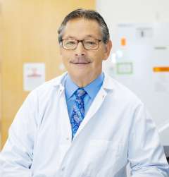 a headshot of scientist Donald Kohn wearing a blue collared shirt and white lab coat