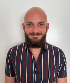 Head-and-shoulders portrait of person with a beard wearing striped shirt