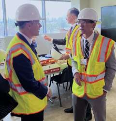 CMO Dr. Erick Cheung and CNO Patrick Loney wear hard hats before touring the neuropsychiatric hospital construction site.