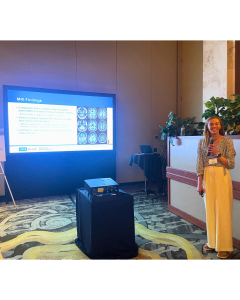 Woman presenting in front of a projector screen at a conference.