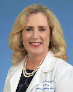 Elaine Reed, PhD, in a white lab coat
