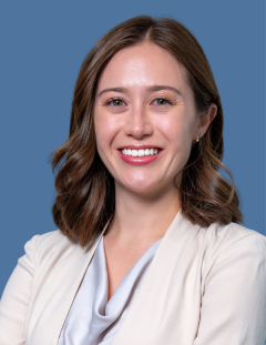 A caucasian woman smiling wearing a white blazer.