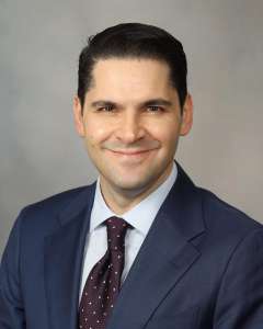 Man smiling while wearing navy blue suit and tie