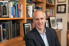 Dr. Geschwind sitting in an office in front of a book case, smiling and looking at the camera