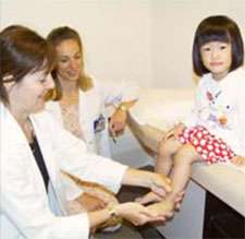 Young girl having her ankle examined by a doctor